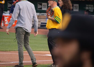 Baseball coach Chris Kyriacou throws the ceremonial first pitch at the Oakland Coliseum