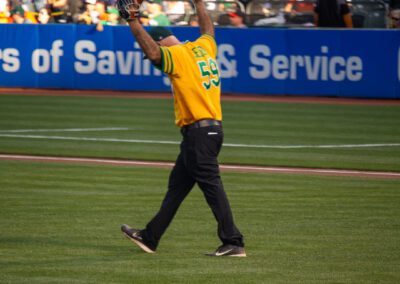 Baseball coach Chris Kyriacou throws the ceremonial first pitch at the Oakland Coliseum