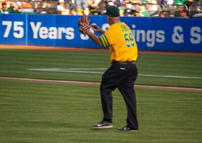 Baseball coach Chris Kyriacou throws the ceremonial first pitch at the Oakland Coliseum
