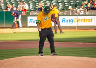 Baseball coach Chris Kyriacou throws the ceremonial first pitch at the Oakland Coliseum