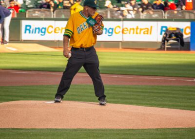 Baseball coach Chris Kyriacou throws the ceremonial first pitch at the Oakland Coliseum