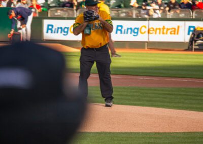 Baseball coach Chris Kyriacou throws the ceremonial first pitch at the Oakland Coliseum