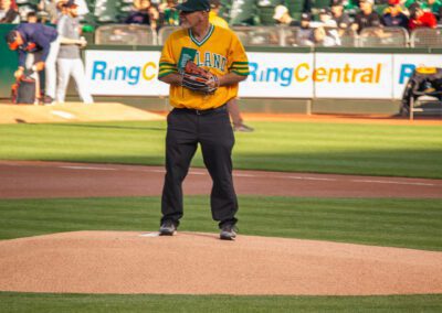 Baseball coach Chris Kyriacou throws the ceremonial first pitch at the Oakland Coliseum