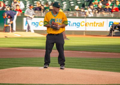 Baseball coach Chris Kyriacou throws the ceremonial first pitch at the Oakland Coliseum