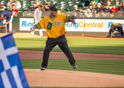 Baseball coach Chris Kyriacou throws the ceremonial first pitch at the Oakland Coliseum